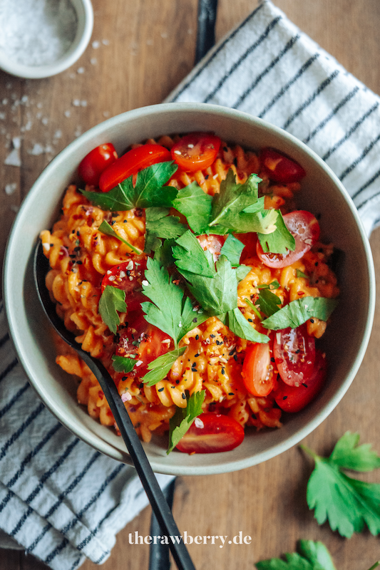 Nudeln in Schüssel mit roter Soße aus Paprika mit Tomaten und Koriander